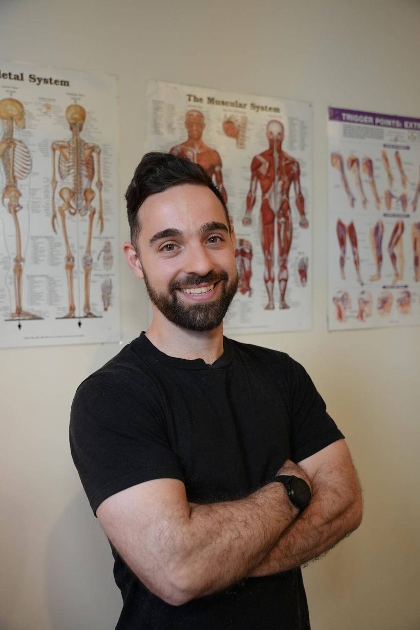 Chris Di Losa standing in front of anatomy charts
